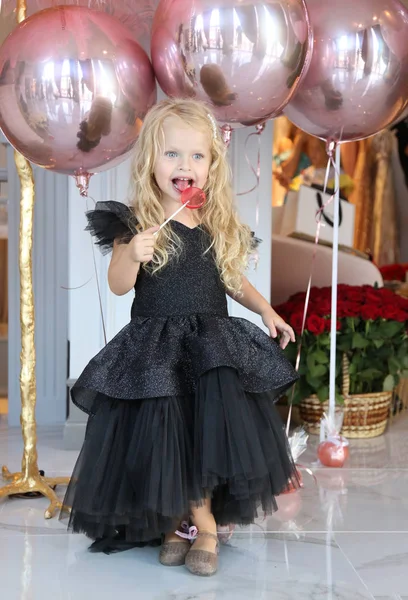 Sarışın, kıvırcık saçlı, zarif elbiseli güzel bir kız.