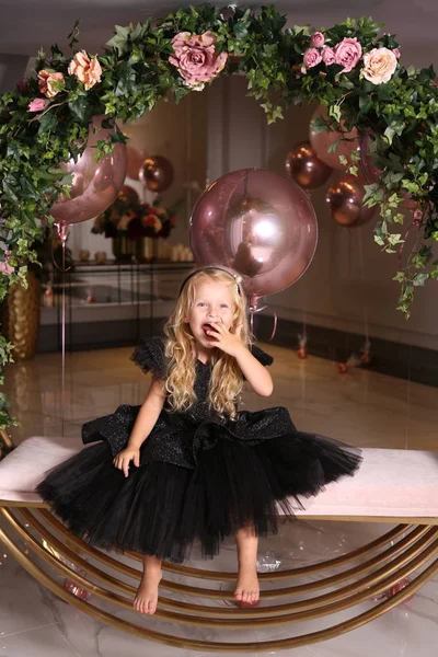 Sarışın, kıvırcık saçlı, zarif elbiseli güzel bir kız.