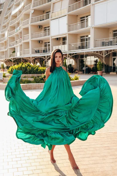 Belle fille aux cheveux foncés dans une élégante robe de soie verte et une — Photo