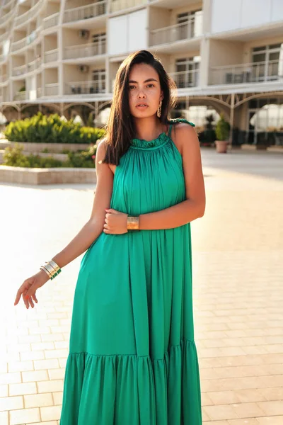 Красива дівчина з темним волоссям в елегантній зеленій шовковій сукні і — стокове фото