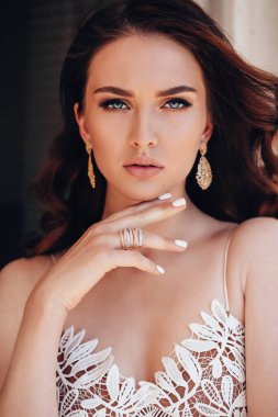 Moda stüdyosu fotoğrafı. Koyu saçlı, takılı, lüks elbiseli güzel bir kadın.