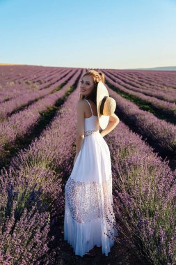 Güzel, sarı saçlı, şık elbiseli, lavanta tarlalarında poz veren aksesuarlı seksi bir kadının moda fotoğrafı.