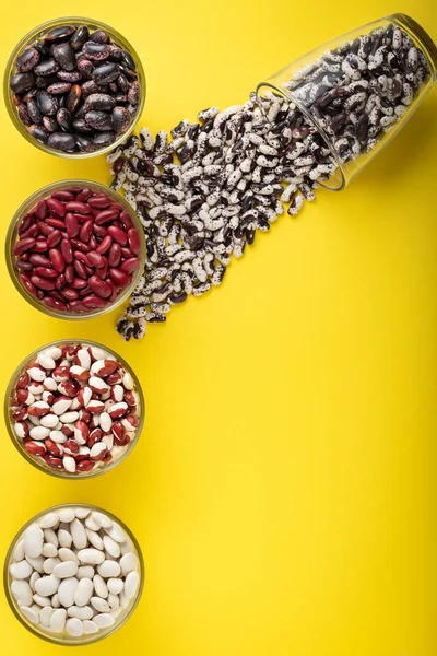 Few Glass Jars Colored Bean Yellow Background Red Black White — Stock Photo, Image