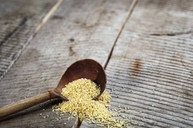 Eski ahşap arka plan üzerinde rustik tahta kaşık darı gluten ücretsiz tahıl.