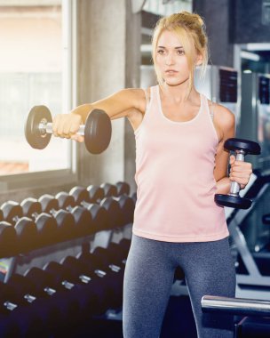 Genç kadın eğitim salonunda dumbbell ile
