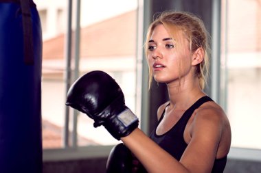 Çekici Bayan boks eldiven eğitim odasında bir çantayla delme