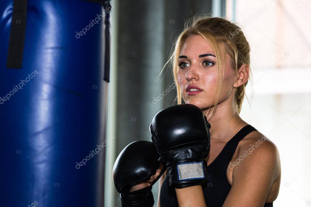 Young female punching a bag with boxing glove