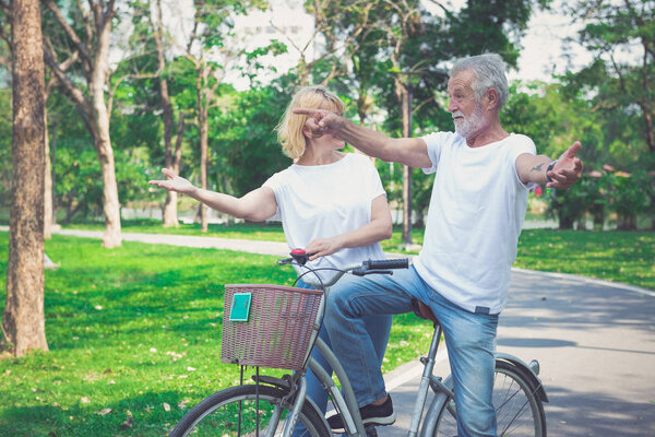 Happy elder couple riding a bicycle in the park