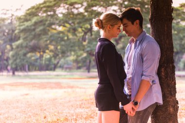 Birbirine aşık genç bir çift parkta sarılıyor.