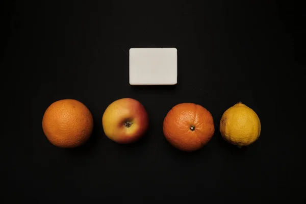 Natural orange soap manual manufactures against juicy fresh fruits on a black background
