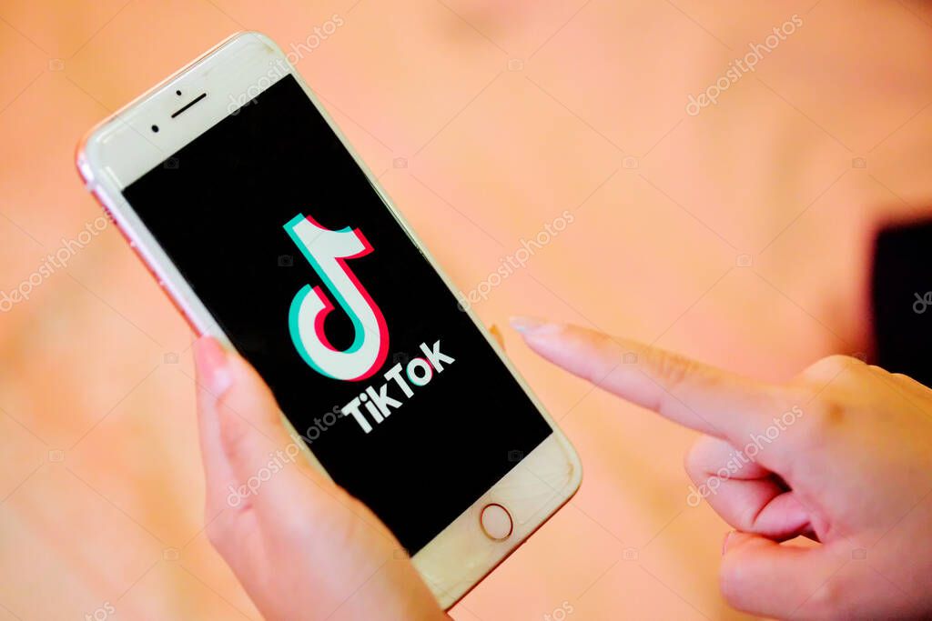 Nakhonratchasima, Thailand - May 31, 2020 : Tik Tok application information icon on Apple iPhone 8 close-up,finger about to touch it.which is a popular social media network is app to create and share videos on the internet.