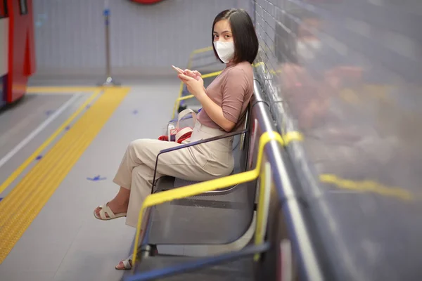 Mujer Asiática Sentada Sosteniendo Teléfono Celular Estación Tren Usar Protector — Foto de Stock