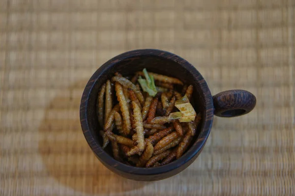 Edible Insects Bamboo Caterpillars in cup on a bamboo place mat