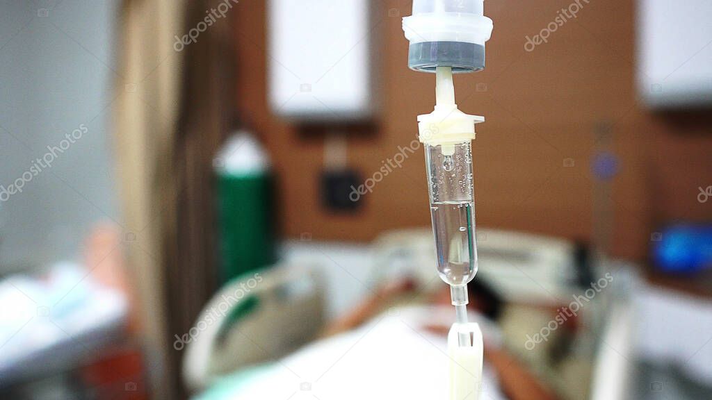 Focus the hanging saline solution with blur patient background. Illness and treatment