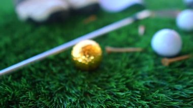Yeşil çimlerin üzerinde çizmeleri olan golf topları ve golf sopalarının yakın çekim görüntüleri.
