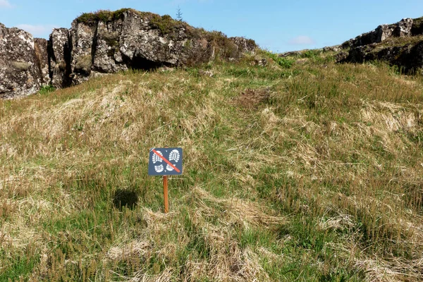 Don't walk on the meadow. Sign with crossed out shoe soles