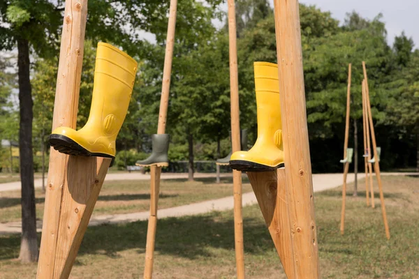 Yellow rubber boots on wooden stilts in the park. Abstract decoration
