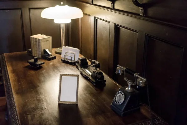 Old wooden desk in the retro office with light and telephone