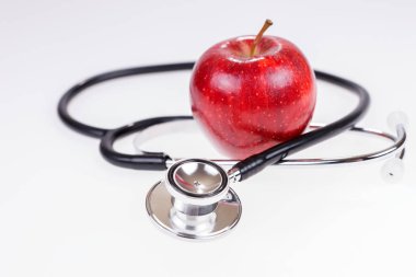 Elma ve stetoskop beyaz izole. Sağlıklı beslenme ve yaşam tarzı kavramı