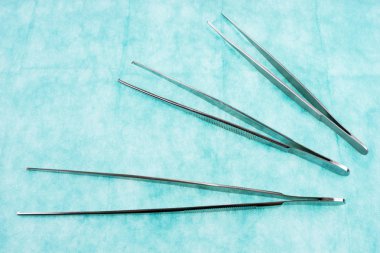 Yeşil gazlı bez üzerinde çeşitli cımbız. El metal aracı. Sağlık ve tıp