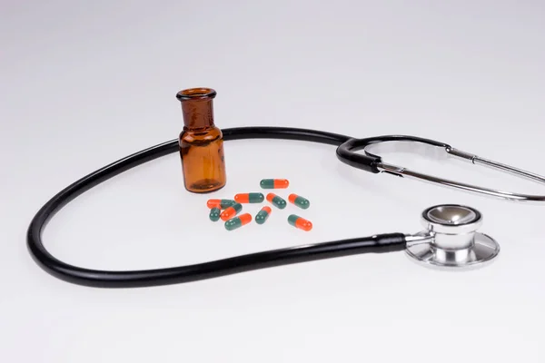 Stethoscope and colorful medical pills poured out of the glass