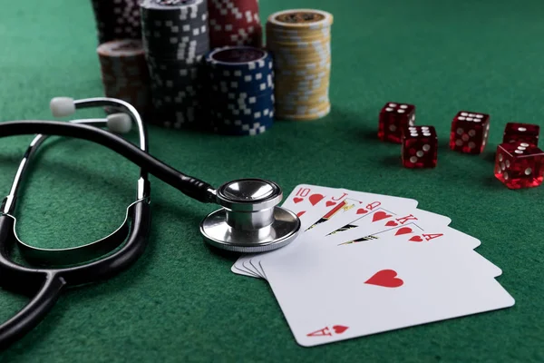 Stethoscope, red cubes and poker playing cards as a gambling with your health concept. Royal flush of hearts