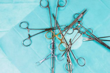 Ameliyat masasında kaos var. Cerrahi makas ve yeşil gazlı bez kelepçeler. Tıbbi aletler
