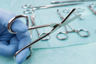 Erkek doktor yeşil arka plan üzerinde bandaj makas tutan. Tıbbi nesne