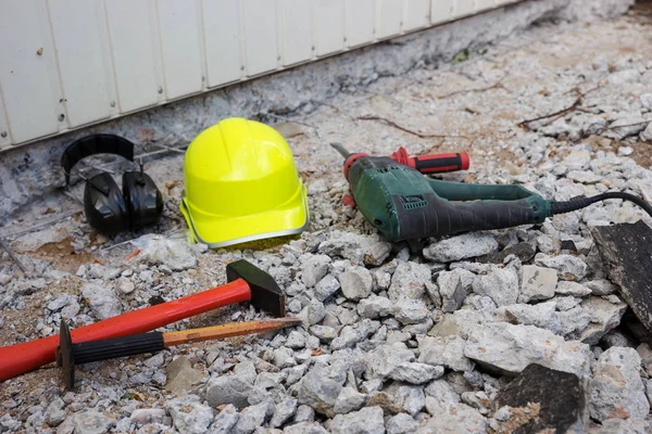 Electric hammer helmet and hearing protection lying on the rubble. Occupational safety at the construction site