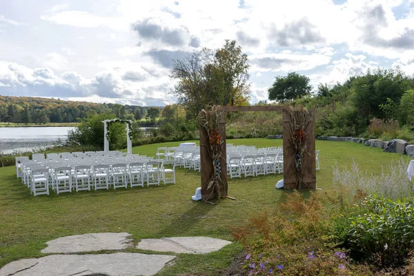 湖畔で結婚式の場所 アーチの両側に花や白い椅子で飾られた結婚式のアーチ屋外 — ストック写真