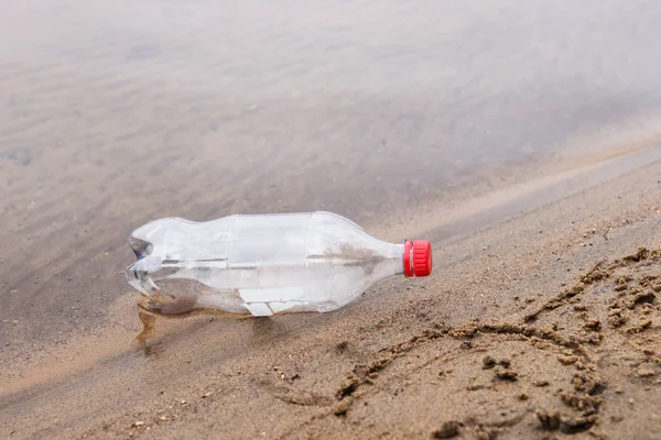 Çöpe atılmış plastik şişe kumsalda yatıyor.
