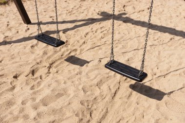 Parktaki kumların üzerinde çocuklar için boş salıncak.