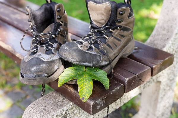Broken hiking boots after the autumn hike on the wooden bench