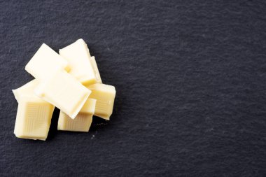 Siyah arkaplanda beyaz çikolata parçaları var.