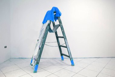 Boya pantolonlu, mavi tişörtlü ahşap merdiven.