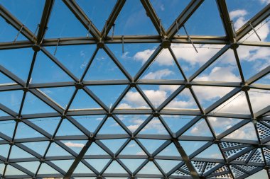 Modern mimari şeffaf cam çatılı mükemmel üçgen şekilli alüminyum yapı, mavi gökyüzünü beyaz bulutlu gösteriyor. 