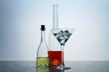 İki berrak kristal şişe ve bir bardak, kırmızı ve sarı sıvı, boş arkaplanda. Barda buzlu güzel bir kokteyl..