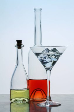 İki berrak kristal şişe ve bir bardak, kırmızı ve sarı sıvı, boş arkaplanda. Bardaki güzel kokteyl seti..