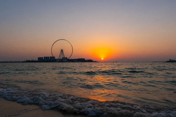 Sunset over the sea view to the Dubai Eye giant Ferris at artificial island Bluewaters Island  close to JBR beach. Amazing sunset on the beach in UAE.