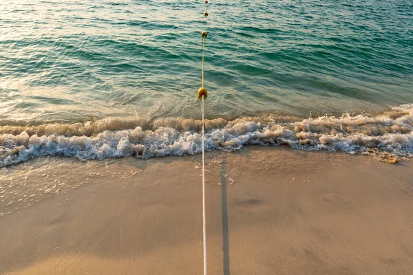 用绳子连在一起的黄色塑料漂浮浮标在海滩和海面上 海上或海上暑假的完美例证 — 图库照片