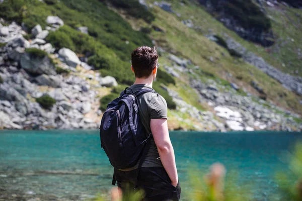 Dağ yürüyüşü sırasında dağ ve göllerin arka planında sırt çantalı bir adam..