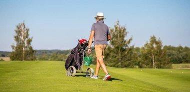 Golf sahasında pozisyon değiştiren bir adam. Golf oyuncusu golf sopasıyla yürüyor..