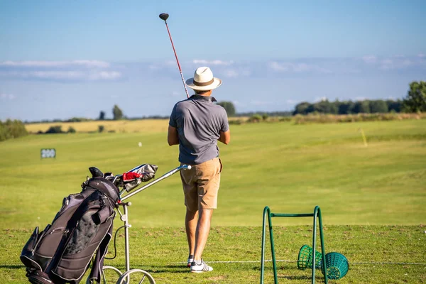 Golfçü topa vurduktan sonra golf sahasına doğru bakıyor.