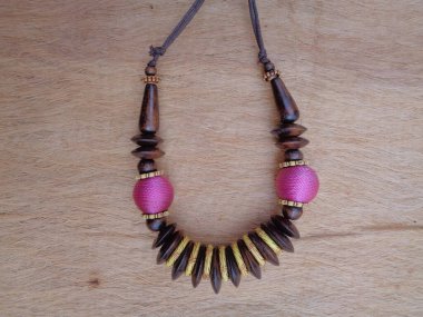 Kahverengi arka planı olan tahta bir kolye. Ahşap arka plandaki kolye..