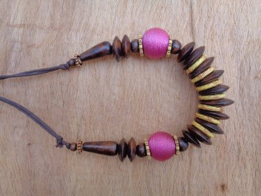 Kahverengi arka planı olan tahta bir kolye. Ahşap arka plandaki kolye..