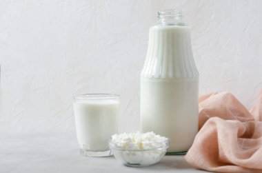 Bardakta ev yapımı mayalanmış içecek kefir, süzme peynir, beyaz arka planda. Ekşi süt içeceği, maya mayası mayası, bağırsak sağlığı konsepti. Modaya uygun yiyecek ve içecekler.