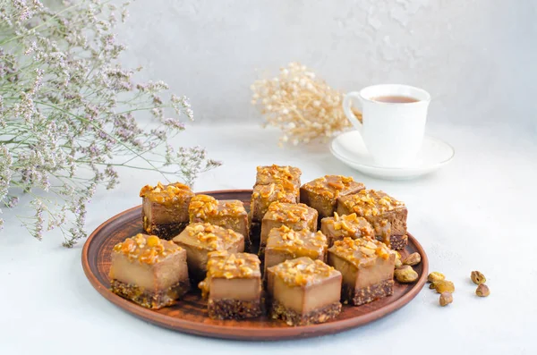 Raw vegan dessert. Chocolate bars with nuts and dates on a white background with a cup of tea. Healthy lifestyle and vegan sweets concept. Vegetarian breakfast. Copy space