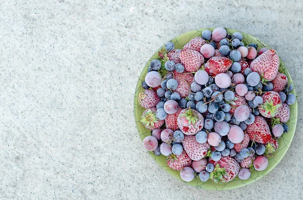 Gefrorene Erdbeeren, schwarze Johannisbeeren, Blaubeeren, Stachelbeeren mit Raureif auf grauem Hintergrund. Flache Lage, Draufsicht. Kopierraum. — Stockfoto