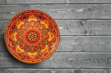 Dekoratif seramik plakalar el gri ahşap arka plan üzerinde akrilik boyalar ile nokta desen boyalı. Kopyalama alanı.