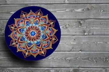 Dekoratif seramik plakalar el gri ahşap arka plan üzerinde akrilik boyalar ile nokta desen boyalı. Kopyalama alanı.